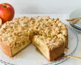 Ein saftiger Apfelkuchen mit Streuseln, ein Stück herausgeschnitten, daneben Äpfel.