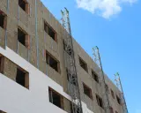 Fachada de edificio en construcción, con aislamiento térmico y andamios. Un plan rehabilita la estructura para mejorar su eficiencia energética.