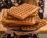 Une assiette débordante de gaufres dorées, parfaites pour une recette de gaufres croustillantes et moelleuses. Un délice à partager !