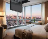 Camera da letto con vista su New York, dove una tv nascosta a soffitto scompare quando non serve, lasciando spazio al panorama.