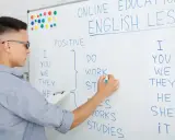 Chłopak pisze na tablicy "English Lesson". To materiał na blog język angielski o gramatyce.