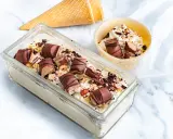 Lody Kinder Bueno w pojemniku i wafelku, posypane orzechami i czekoladą.