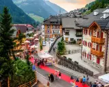 Festa a Santa Cristina Val Gardena con gente, bancarelle e un tappeto rosso.
