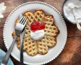 En vacker, hjärtformad våffla, perfekt för en fika. Dessa glutenfria våfflor serveras med vispad grädde och sylt.