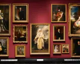 A gallery wall displays several portraits, including a striking portrait of Omai in traditional attire, surrounded by other historical figures.