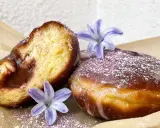 Pączki według przepisu Ewy Wachowicz, z lukrem i fiołkowym pyłkiem, ozdobione kwiatami.