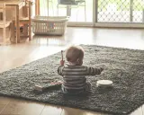 Liten bebis sitter på en matta och leker med en xylofon och en tamburin. En perfekt start på en checklista bebis för musikaliska äventyr.