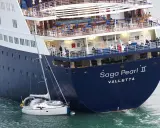La nave da crociera "Saga Pearl II" è imponente accanto a una piccola barca a vela, mostrando la differenza tra nave e traghetto.