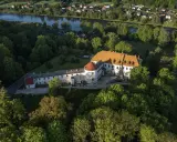Zamek w Lesku otoczony zielenią, z widokiem na rzekę i miasteczko.