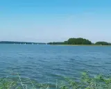 Spokojne jezioro Jagodne, gdzie żaglówki suną po wodzie, a w głębinach czają się ryby.