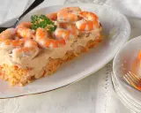 Pastel de pescado para Navidad, cubierto con una cremosa salsa rosada y adornado con gambas. Un entrante festivo y delicioso.