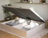 Un canapé de madera clara con la tapa abierta, revelando un gran espacio de almacenamiento para ropa de cama y almohadas.