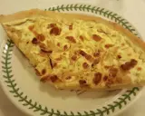 Part de quiche lorraine, une des spécialités lorraines, sur une assiette décorée de feuilles vertes.
