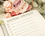 Bukiet róż i eukaliptusa obok notatnika z napisem "Wedding Checklist". Idealna inspiracja, co zabrać na wesele.