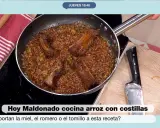 Un delicioso arroz con costillas se cocina en una sartén, con trozos de carne jugosa y arroz dorado.