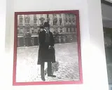Ritratto di Franz Kafka, figura iconica che ci fa chiedere chi era Kafka, in piedi su un selciato con un edificio sullo sfondo.