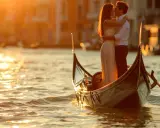 Un couple s'embrasse tendrement dans une gondole, baigné par la lumière dorée du coucher de soleil. Venise, ville des amoureux, offre un cadre idyllique pour cet instant magique.