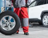 Mecánico con una rueda motriz de coche lista para ser instalada.