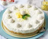 Eine köstliche Raffaello Torte ohne Backen, dekoriert mit Kokosbällchen, Ananas und Minze.