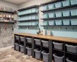 Des étagères bleues et grises organisent l'espace, parfait pour savoir comment stocker des vêtements dans un garage. Des paniers et bacs pour un rangement optimal.