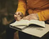 Mani che scrivono su un quaderno aperto, ispirate dalle riviste letterarie italiane.