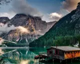 Lago alpino con baita in legno e montagne nebbiose. Curiosità sul Trentino Alto Adige: un luogo da fiaba.