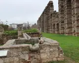 Eine Katze sitzt auf alten Steinen vor dem römischen Aquädukt von **Mérida, Spanien**.
