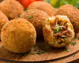 Chrupiące arancini, pyszne włoskie dania z ryżu, mięsa i groszku, posypane parmezanem.