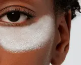 Primo strato di cipria prima del fondotinta, evidenzia la texture della pelle e la preparazione per un makeup impeccabile.