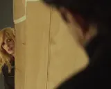 Donna bionda spia da dietro un pannello, forse un colpo di scena nel **promises trama finale**.