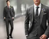 A man models a sharp grey suit with a white dress shirt, dark tie, and boutonnière. Perfect for any formal occasion.