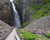 Vacker vattenfall i en ravin, med en träbro som leder besökare längs en av Sveriges många vandringsleder.
