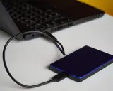 Un disque dur externe bleu est connecté à un ordinateur portable. Un guide pour comment choisir un disque dur.
