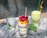 Pyszny koktajl białkowy z kawałkami smoczego owocu i mango. Obok zielony smoothie i szklanka z lodem.