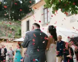 Novios bajo una lluvia de confeti en forma de corazón. Los invitados lanzan confeti, creando un ambiente festivo, perfecto para las canciones de boda.