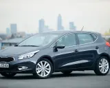 Ciemnoszary Kia Ceed 1.6 benzyna stoi na tle miejskiego krajobrazu.