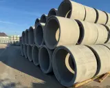 Stos betonu kręgów betonowych do studni, gotowych do budowy podziemnych konstrukcji.