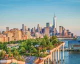En grönskande park på pelare med New Yorks skyline i bakgrunden. Perfekt för tips på nya upplevelser i New York.