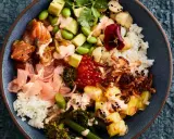 Eine bunte Poke Bowl mit Lachs, Avocado, Edamame, Reis, eingelegtem Ingwer und knusprigen Zwiebeln.