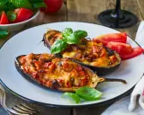 Melanzane ripiene senza carne, dorate e filanti, guarnite con basilico fresco e pomodoro. Un piatto vegetariano invitante.