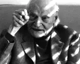 Ritratto di un anziano con pugno alzato, in memoria di Ungaretti. Le rughe sul volto e la luce che lo illumina creano un'atmosfera intensa.
