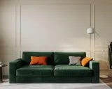 Elegancki salon w odcieniach butelkowej zieleni i beżu. Miękka sofa, nowoczesna lampa i kaktus tworzą przytulną atmosferę.