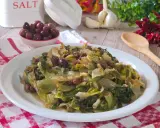 Scarola in padella con olive, pinoli e uvetta, un contorno saporito e colorato.