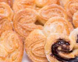 Deliciosas palmeritas de hojaldre espolvoreadas con azúcar. Algunas tienen un relleno de chocolate oscuro y brillante.