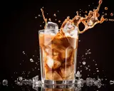 Un café glacé maison éclabousse dans un verre rempli de glaçons.