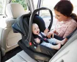 Uśmiechnięta mama patrzy na swoje dziecko w foteliku samochodowym. Ten fotelik dla dziecka do 20 kg zapewnia bezpieczeństwo maluchowi podczas podróży.