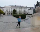 Dziewczynka na trasie traktu królewskiego w Warszawie, obok lwa i pomnika konnego.