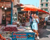 Coppia felice assaggia polpo fritto in un mercato di Palermo in un giorno di sole. Un assaggio autentico della Sicilia.