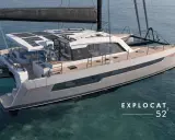 Un catamaran de luxe, un **deriveur integral** moderne, navigue sur des eaux bleues claires. Panneaux solaires sur le toit, design épuré.