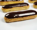 Plusieurs éclairs au chocolat brillants, avec un fondant pour éclair parfait, sont disposés sur fond blanc.